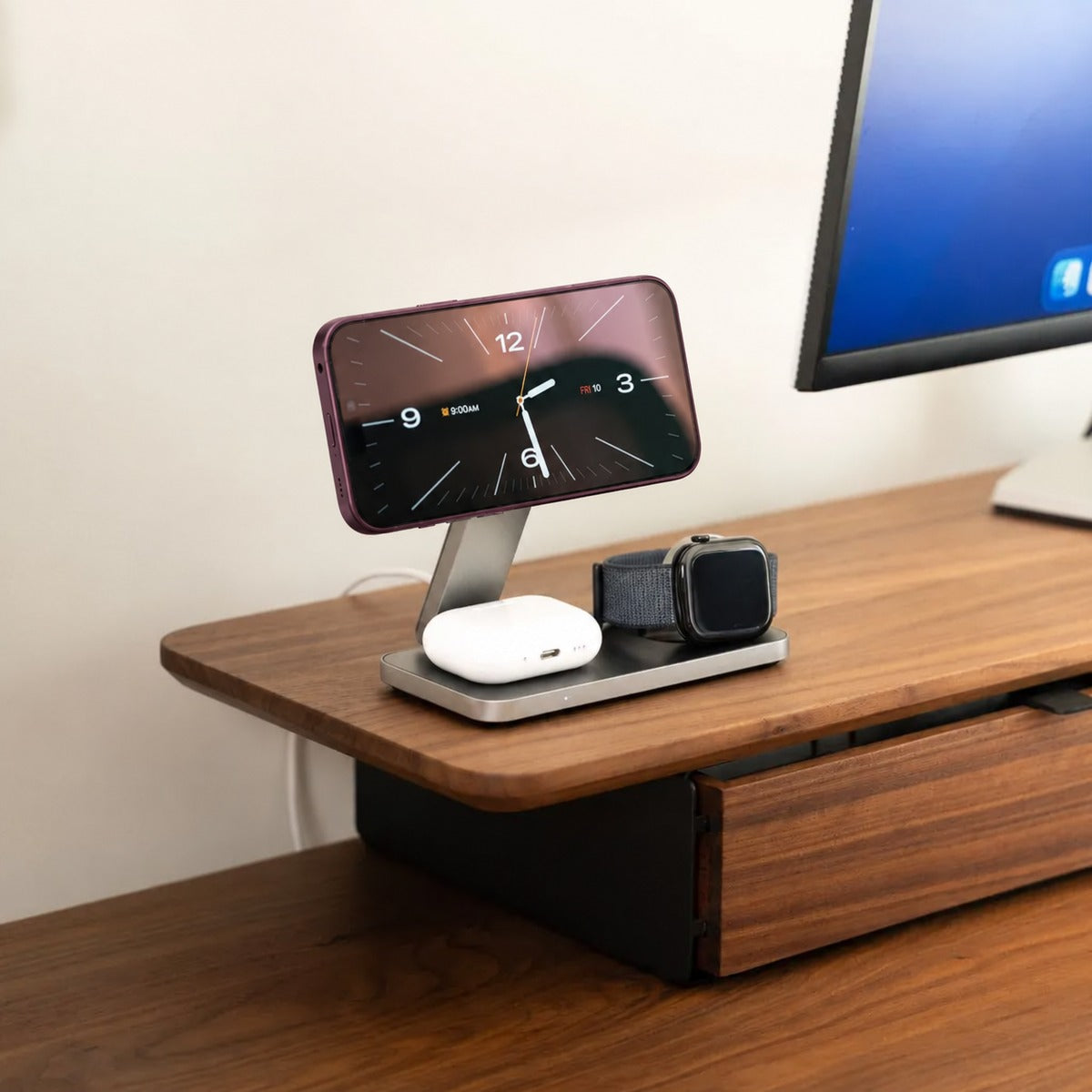 MagFold Base 3-in-1 charging station on a desk with Burgundy iPhone, Apple Watch and AirPods.