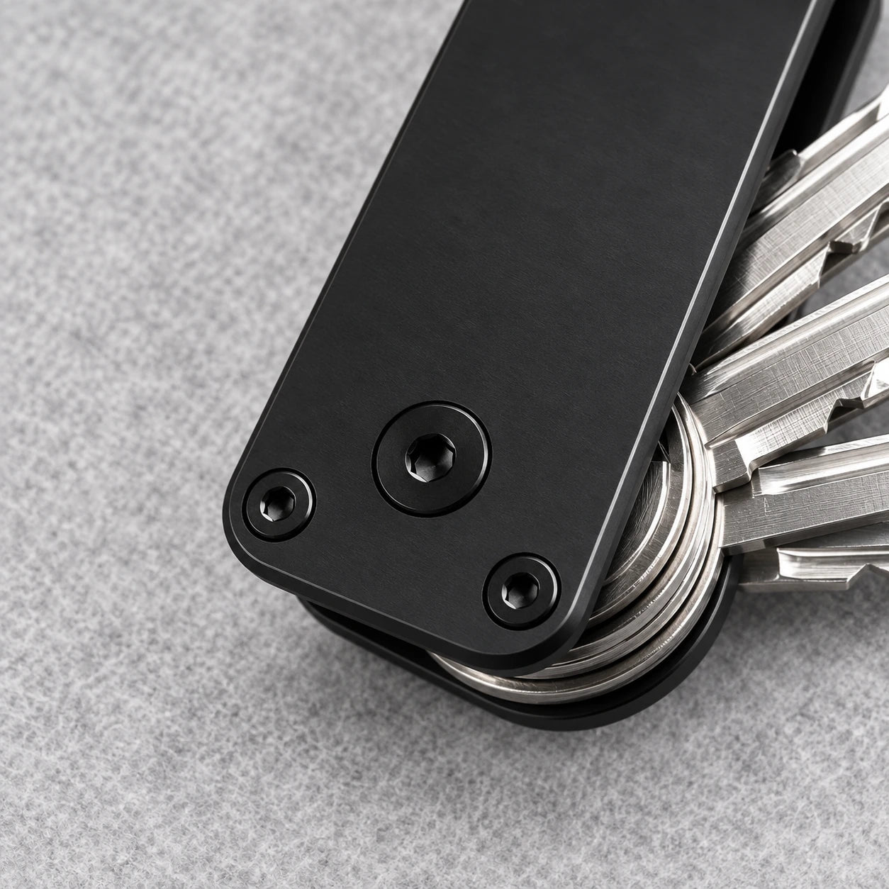 Close-up of the aluminum key organizer's pivot screw, corner screws and stacked keys.