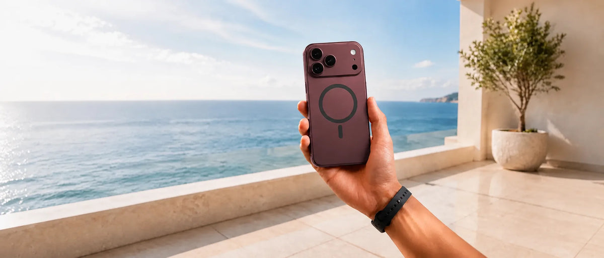 Burgundy magnetic phone case with a black charging ring held by the ocean.