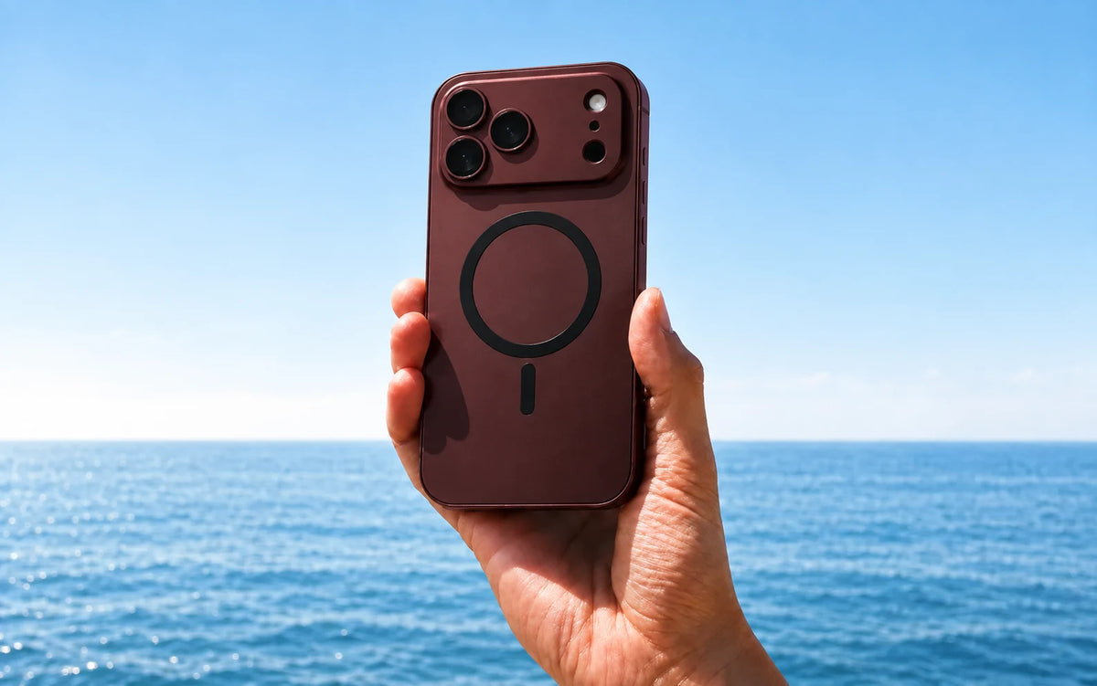 Burgundy magnetic iPhone case held above the sea.