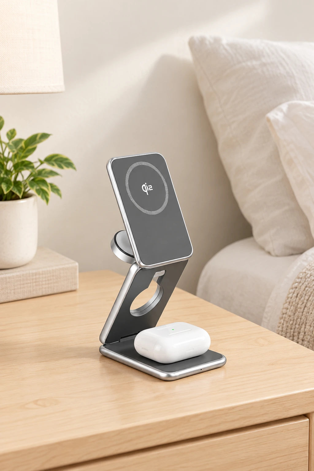 Earbud case resting on the base of the original silver folding charger with its tall Qi2 charging head visible.