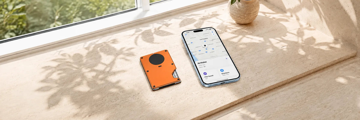 Orange metal tracker wallet beside a phone displaying a location map.